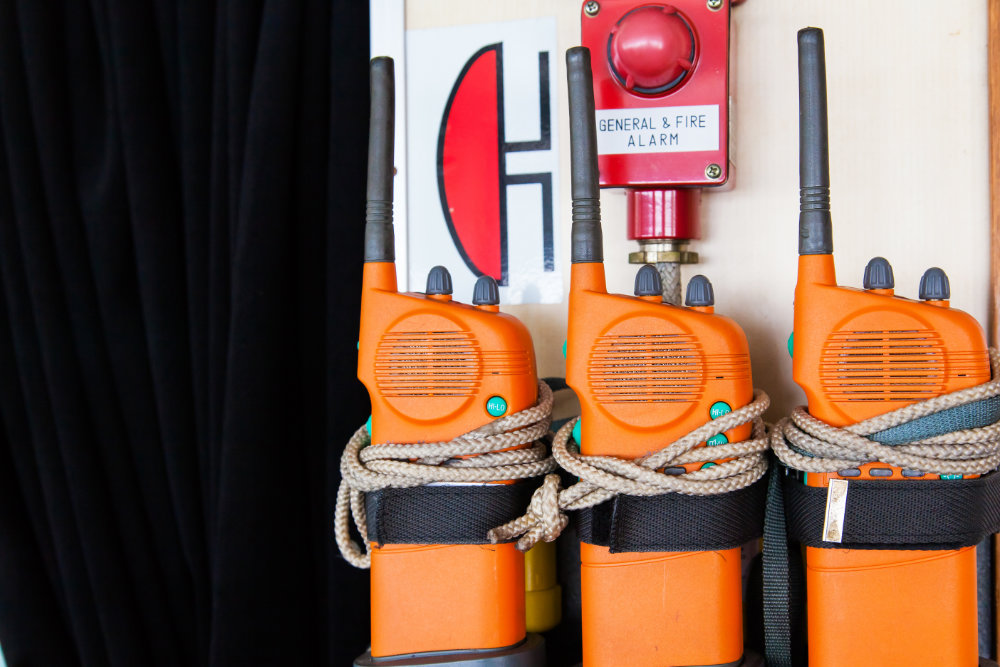 Three orange emergency radios on a ship near an alarm. Apply in case of general or fire alarm.